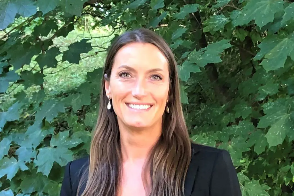 En person som smiler foran en busk