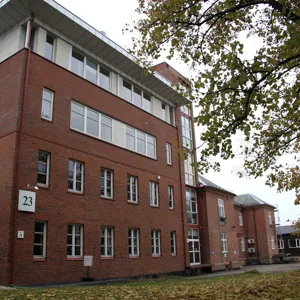 En murbygning med et tre foran seg