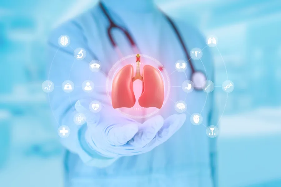 Lege som holder et sett lunger i hendene, omkranset av medisinske ikoner